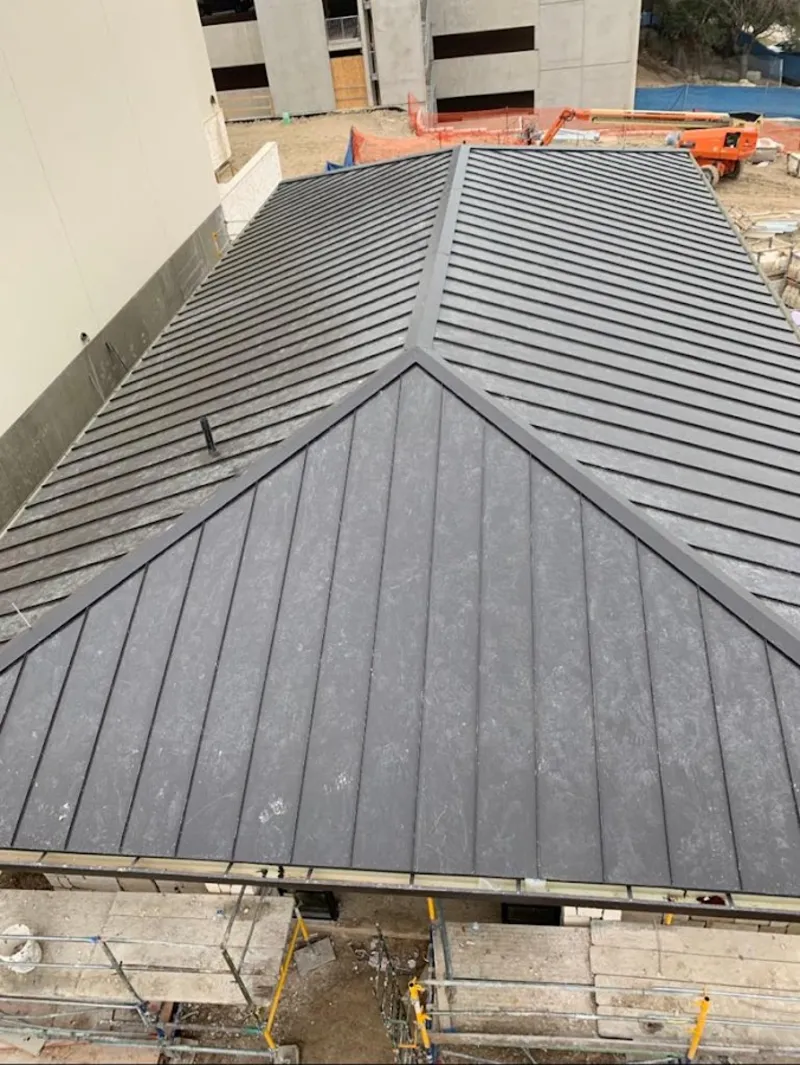 Commercial metal roof construction with crane equipment in Addison